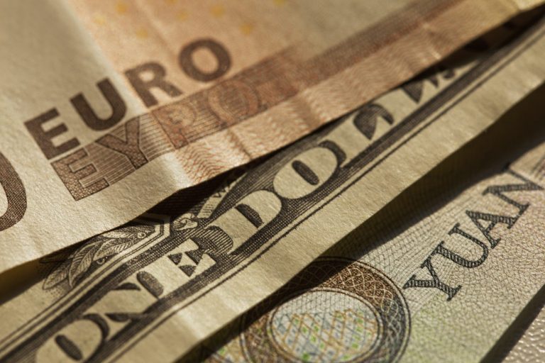 Scheine in Euro, US-Dollar und Yuan übereinandergelegt.